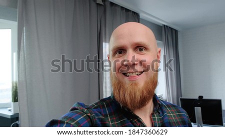 Young Caucasian bald man with a beard shows his apartment by video call on his smartphone. Electronic gadgets, modern technologies. Close-up of the face. 360 degrees Royalty-Free Stock Photo #1847360629