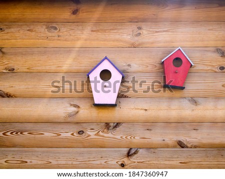 Two bright wooden colorful birdhouses are installed on the wall. Home decor.