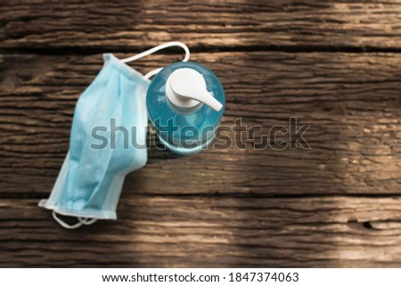 Ear loop face mask in box and sterilized alcohol gel on wood background.