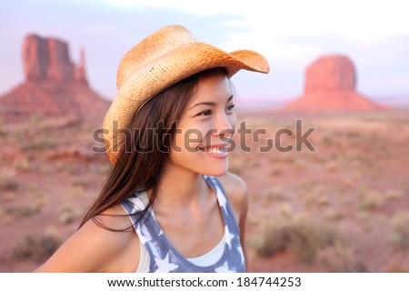 Cowgirl woman happy portrait in Monument Valley wearing cowboy hat. Beautiful smiling multiracial young woman outdoors, Arizona Utah, USA.