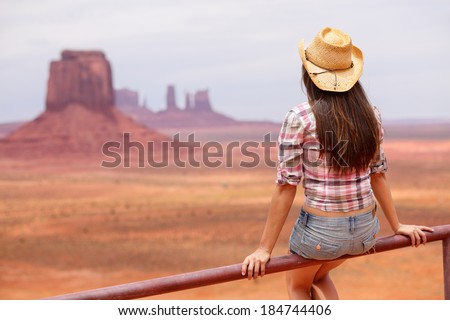 Cowgirl woman enjoying view of Monument Valley wearing cowboy hat. Beautiful young woman on sitting looking outdoors, Arizona Utah, USA.