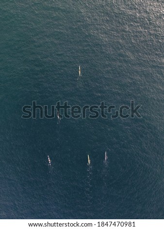 An aerial vertical shot of people in kayak boats paddling in a calm clear ocean water