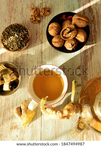 herbal tea in teapot and cup, ginger and walnuts