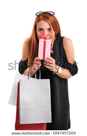 Beautiful young woman in a black dress holding shopping bags and present, isolated on a white background. Shopping concept. Gift concept.