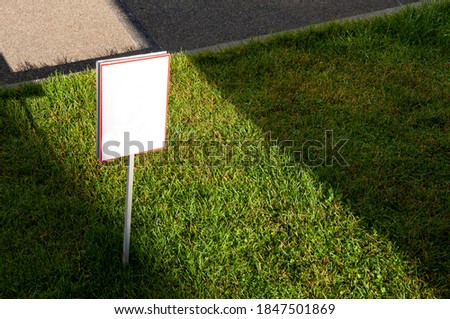 warning sign with green lawn and asphalt background, view from above, the sign is empty