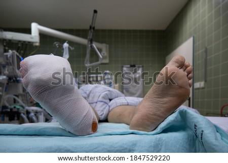 the foot of a patient lying in a hospital bed is wrapped with a bandage