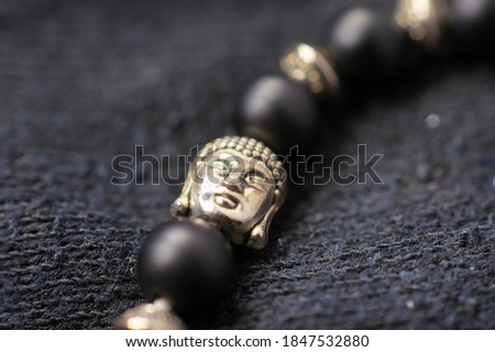 Closeup of Buddha head, black bracelet