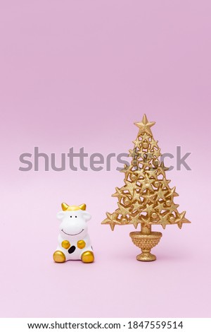 Toy cow and decorative Christmas tree. White ox is the New Year symbol of 2021  in the Oriental calendar. Vertical banner, copy space