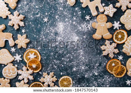 Christmas composition, New Year greeting card. Mockup with festive food decorations and gingerbread cookies on blue background. Copy space.