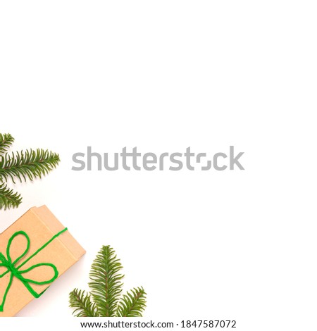 Isolated craft gift box with green ribbon as presenf for Christmas, new year, holliday on white background with fir tree. Flat lay, top view