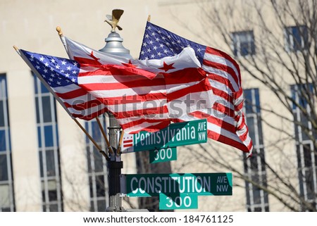 Washington DC, Pennsylvania Avenue and Constitution Avenue junction street signs with DC and United States of America flags on the same post 