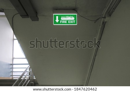 Fire exit words on green sign lamp board, that hanging at the building edge stair