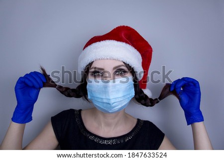 Woman wearing protection face mask against coronavirus. Woman in a mask and Christmas hat. Funny Christmas accessory. Medical mask, Medical gloves, Close up shot, Select focus, Prevention from covid19