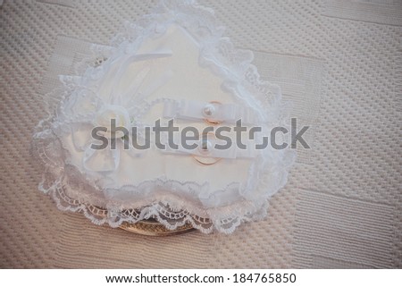 Two wedding rings with white flower in the background.