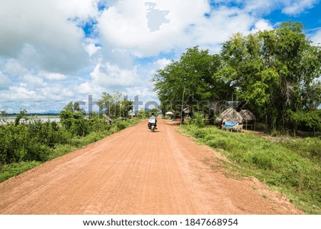 Image of a family in Asia riding a motorcycle in rural countryside Cambodia.