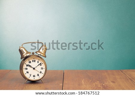 Retro bronze alarm clock on desk front mint green background
