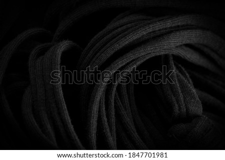 Texture, background, pattern. Fabric in black braids. Knitted knitted background with embossed pattern. Braids in knitting.