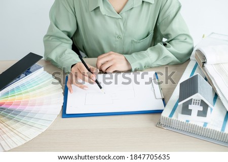 The designer is planning the interior of the house, illustrating and choosing the perfect colors for the new home with sample materials on the desk. Real estate design business Ideas.
