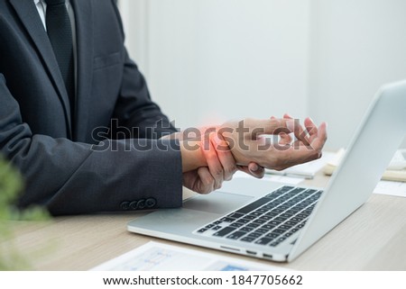Businessman grasping the painful wrist caused by prolonged work on a laptop keyboard. Wrist numbness Arthritis While working at the office.