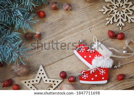 Christmas, New year card with fur tree, dogrose, wooden decoration figures: snowflakes, star, skates on wooden table 