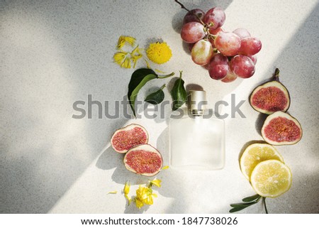 
glass perfume bottle with water drops, lemon and fig wedges on light background with hard shadows. Fresh fruit scent concept. Copy space Royalty-Free Stock Photo #1847738026