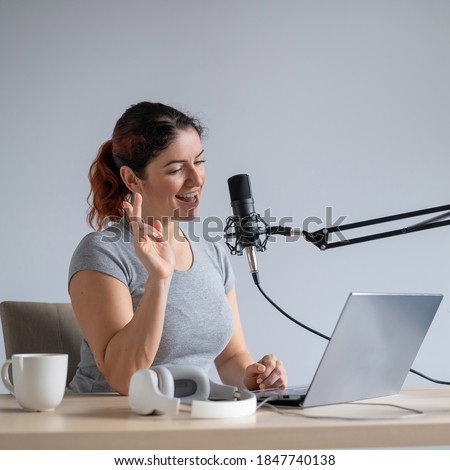 A charming woman radio host is broadcasting live on a laptop. Online radio concept