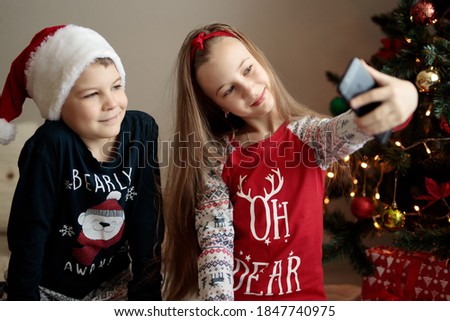 Children in Christmas costumes take pictures of themselves on the phone