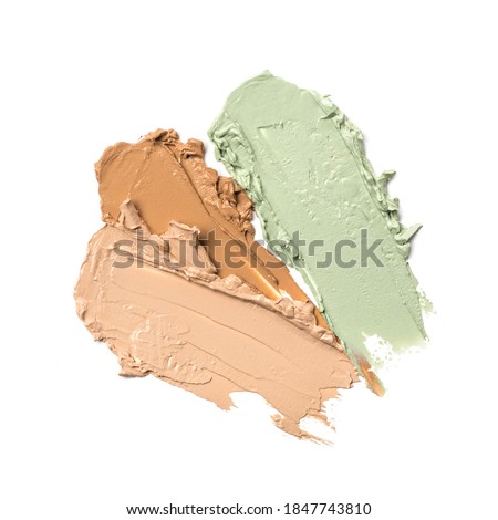 Shades of smudged brush strokes beige and green foundation or concealer as samples of cosmetic beauty products for correcting isolated on white background