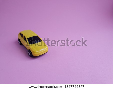 yellow toy car on a pink background, a concept idea of a taxi and delivery of goods during quarantine