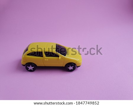 yellow toy car on a pink background, a concept idea of a taxi and delivery of goods during quarantine