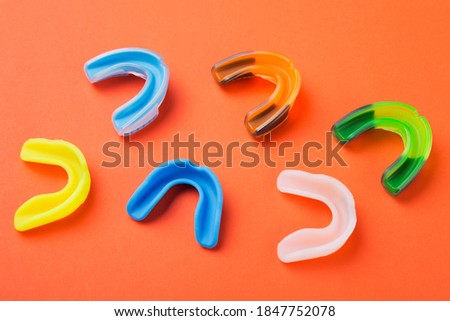 many boxing mouthguards of different colors, lies on an orange background, concept Royalty-Free Stock Photo #1847752078