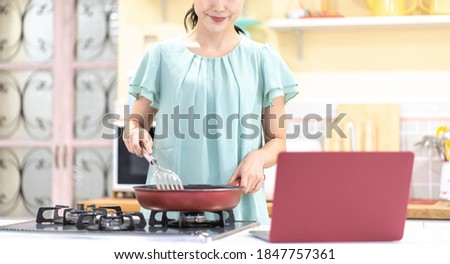 Asian woman looking at a computer in the kitchen of the house