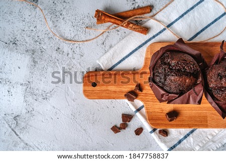 Chocolate cupcakes and cinnamon sticks on a kitchen towel. Food background with copyspace.