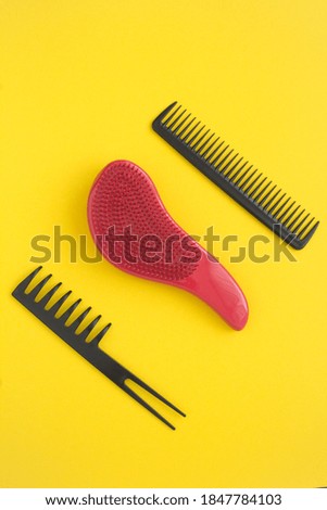 Top view of black and red hair combs on the yellow background