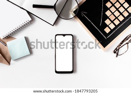 Business flat lay on white background top view. Smartphone mockup, envelope, notebook, credit card, chalkboard, eyeglasses. Business statistic. Career, money, success concept. Workplace organization.