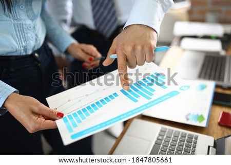 Male and female hand holding charts with business indicators in office. Small and medium business planning and development concept