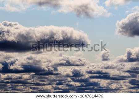 Bright blue sky with dramatic cumulus clouds lit by the daytime sun. Abstract background.