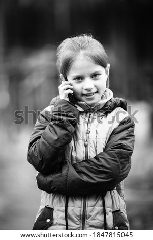 Portrait of little girl talking on the phone. Black and white photography.