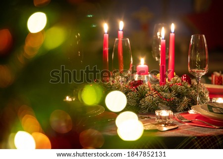 beautifully decorated Christmas table with candles and glasses near the Christmas tree