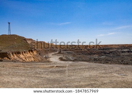 Copper ore open-pit mining. Quarry panorama. Electric mast and quarry machine on blue sky background.