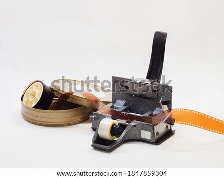 35mm film slitting and splicing tool with negative film roll on white background