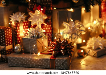 Beautiful Christmas gift boxes on floor near fir tree in room