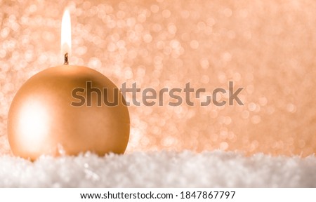 A small Golden candle on a shiny gold background. The idea of celebration