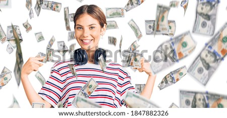 Beautiful caucasian woman with blonde hair wearing gym clothes and using headphones looking confident with smile on face, pointing oneself with fingers proud and happy.