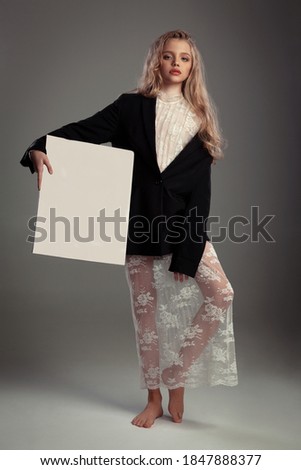 beautiful teenage girl in a black large jacket with a rose in the buttonhole and a blank canvas for artists