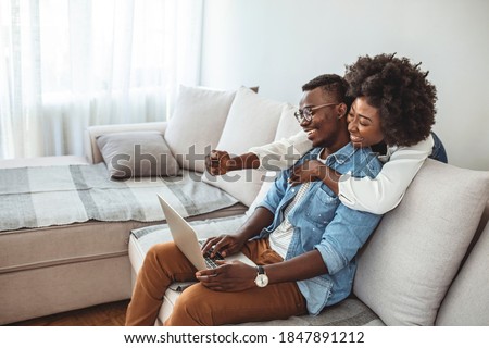 Shot of a young couple using a laptop on the sofa at home. Couch surfing has become their favourite hobby. Shot of a young couple using a laptop while relaxing at home