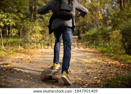 Cropped head of male with backpack spending free time rolling along path in sunny park alone