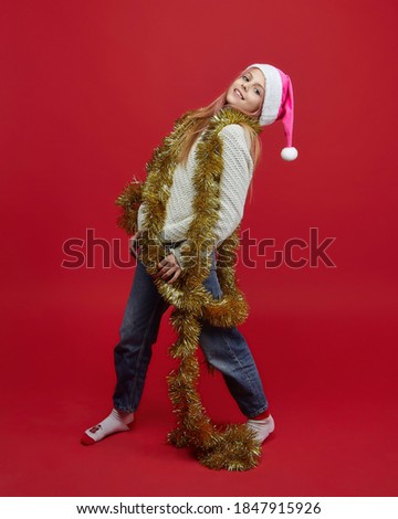 young girl in a Santa hat. photo session in the Studio on a red background