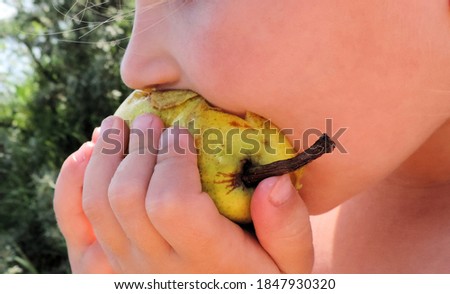     Closeup cute adorable toddler girl  eating pear outside chewing  sitting on the beach