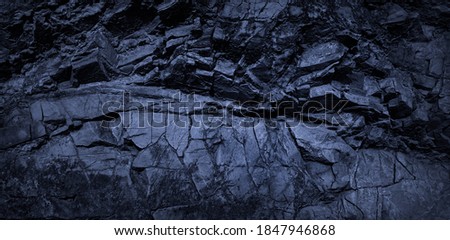  Dark blue rock background. Monochrome toned rocky stone texture. Collapsed weathered mountain surface. Close-up. Deep blue volumetric rock background.                              